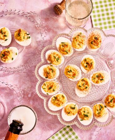 A spread of deviled eggs on a pink background