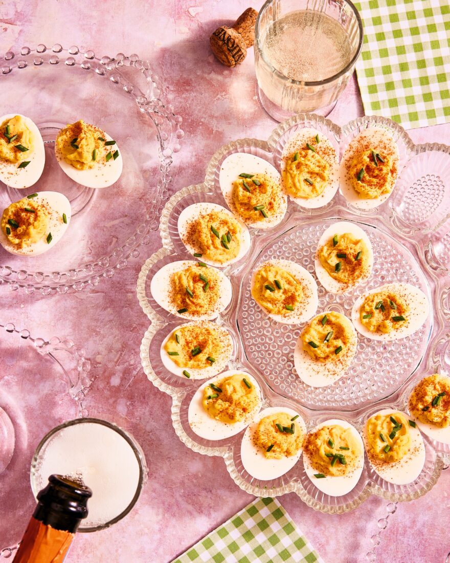 A spread of deviled eggs on a pink background