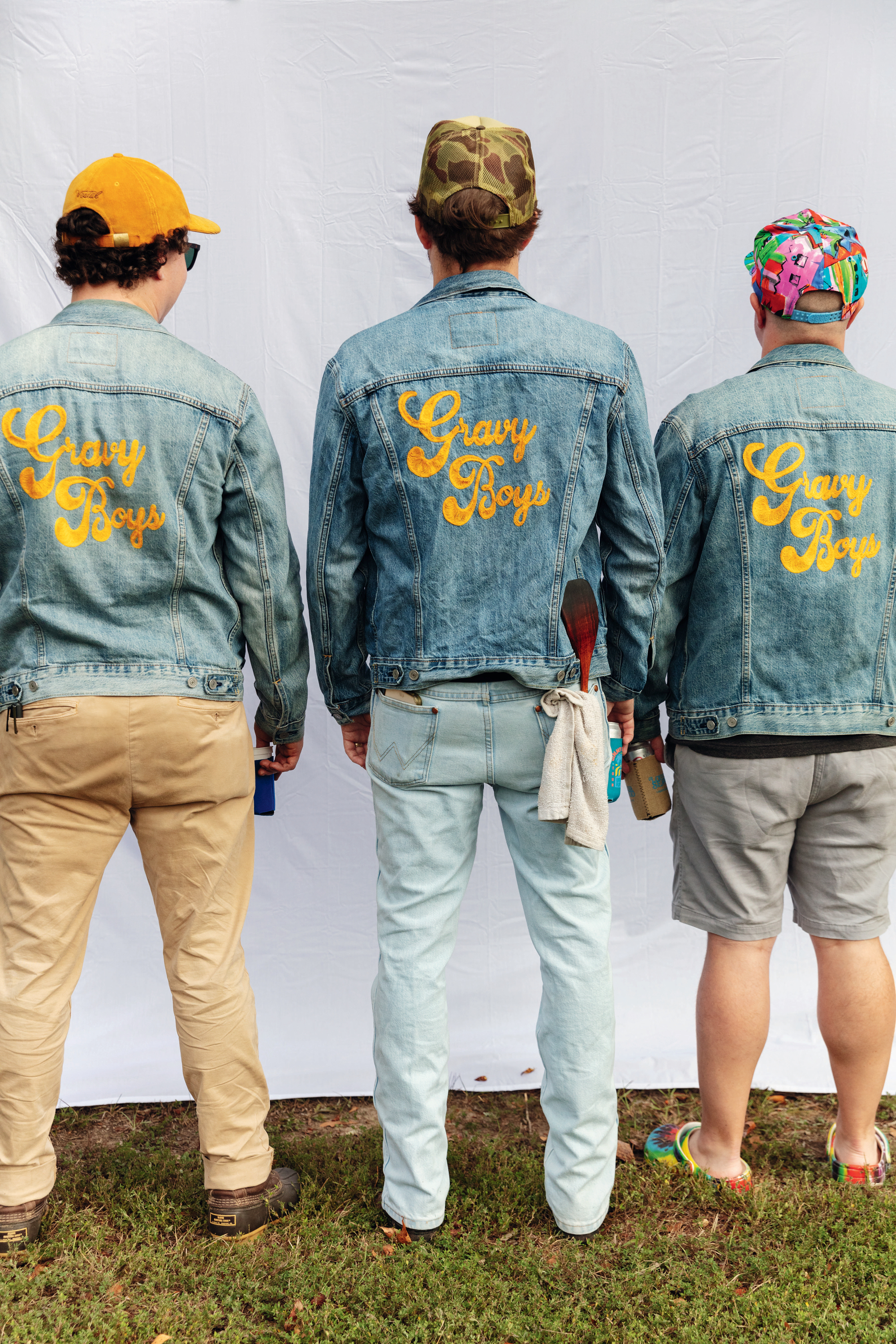 Three men show off denim jackets embroidered with the words "Gravy Boys"