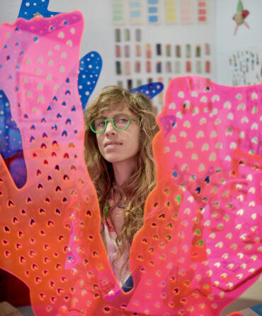 A portrait of a woman behind pink plexiglass coral