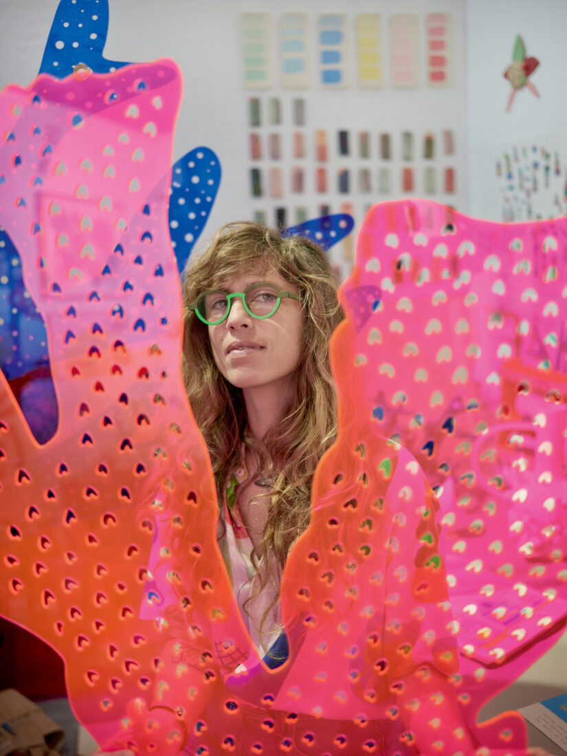 A portrait of a woman behind pink plexiglass coral