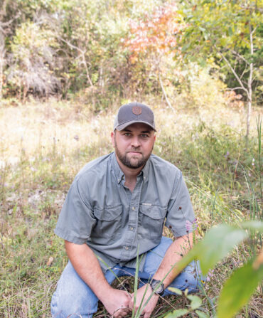 A man crouches in a field