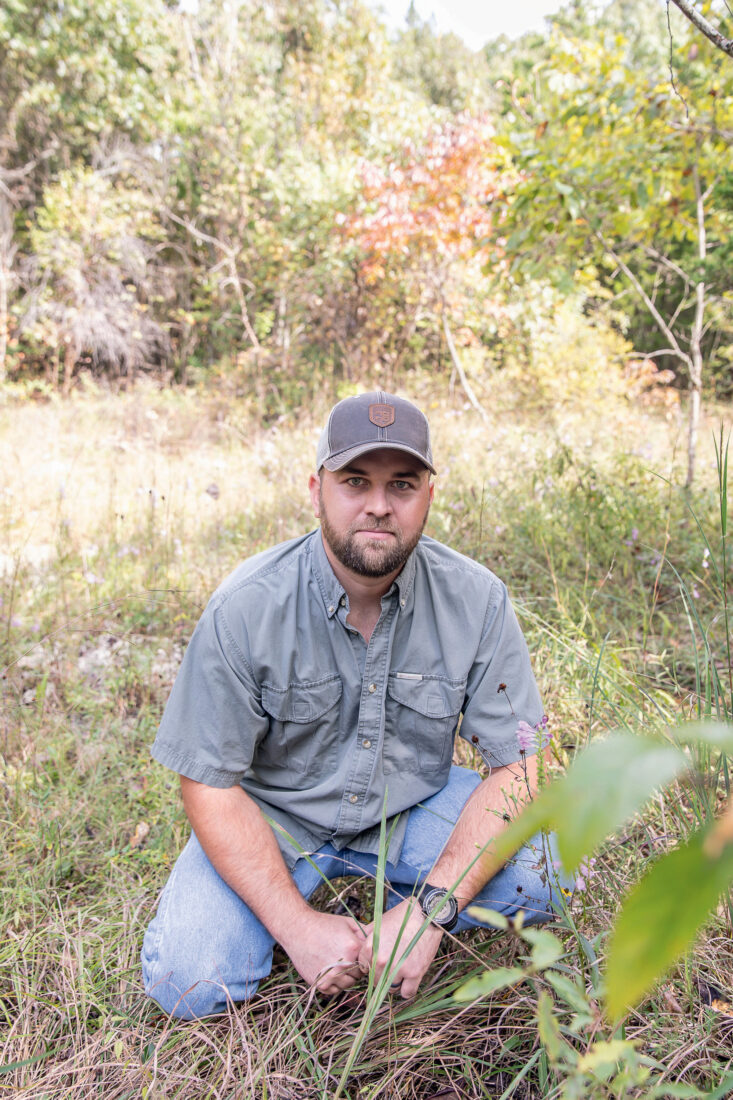 A man crouches in a field