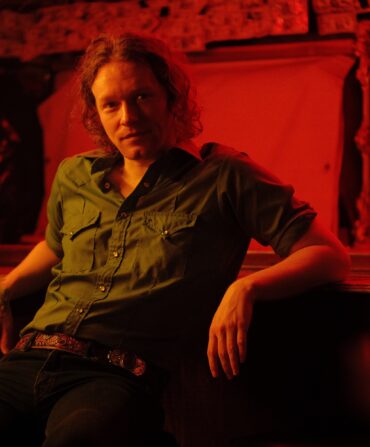 A portrait of a man sitting at a bar in red lighting