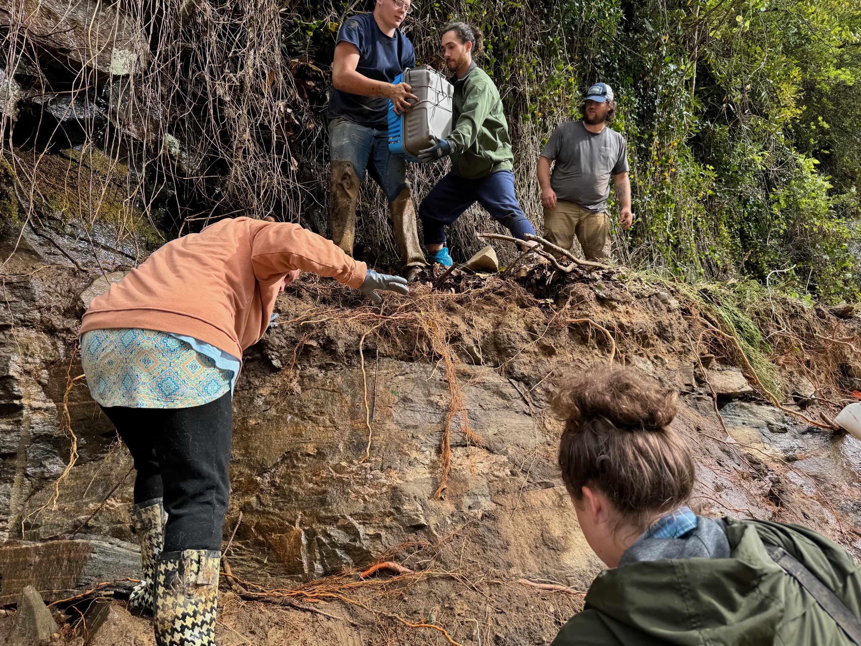 People climb up a muddy slope