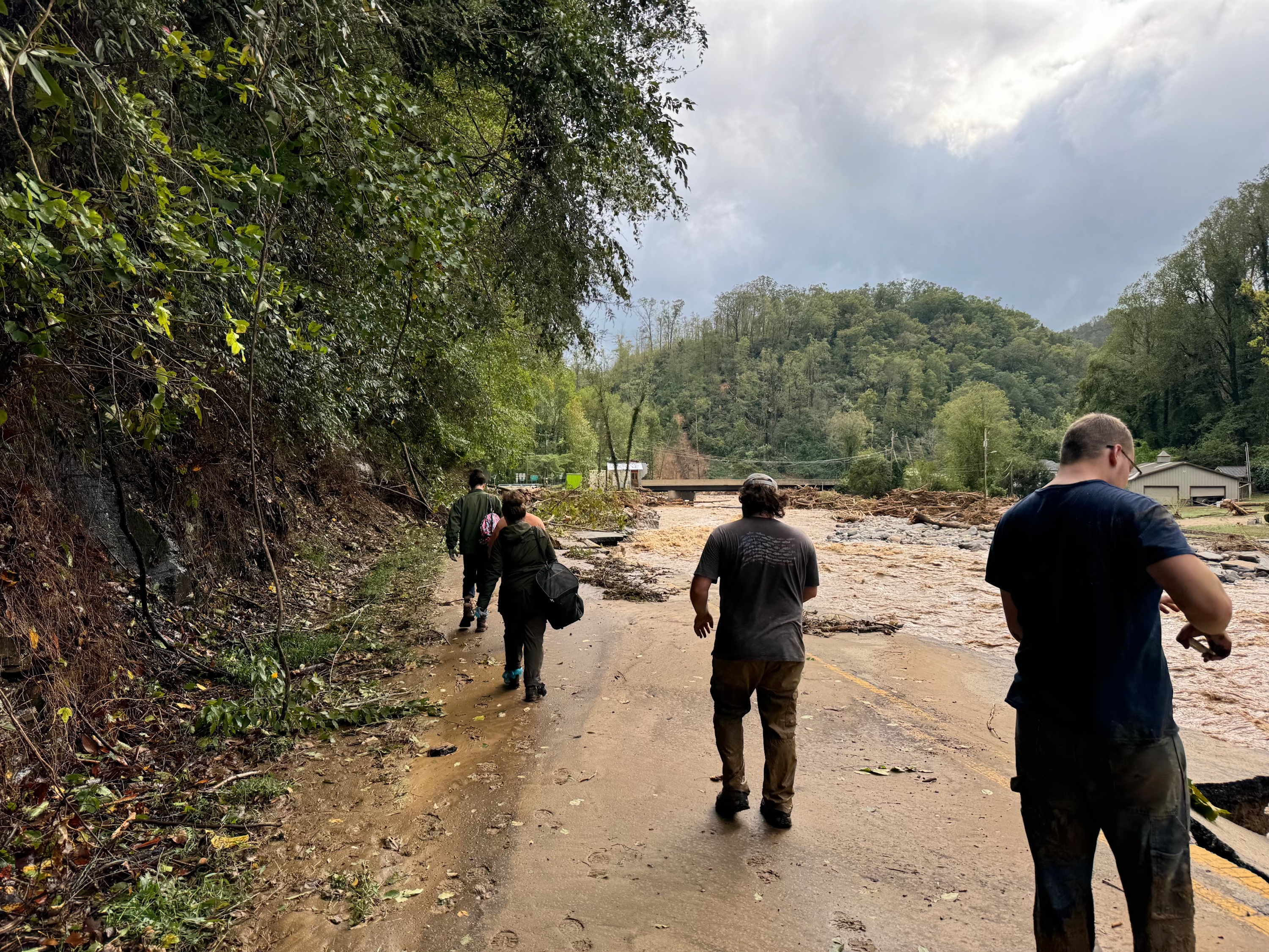 People walk alongside a washed out road