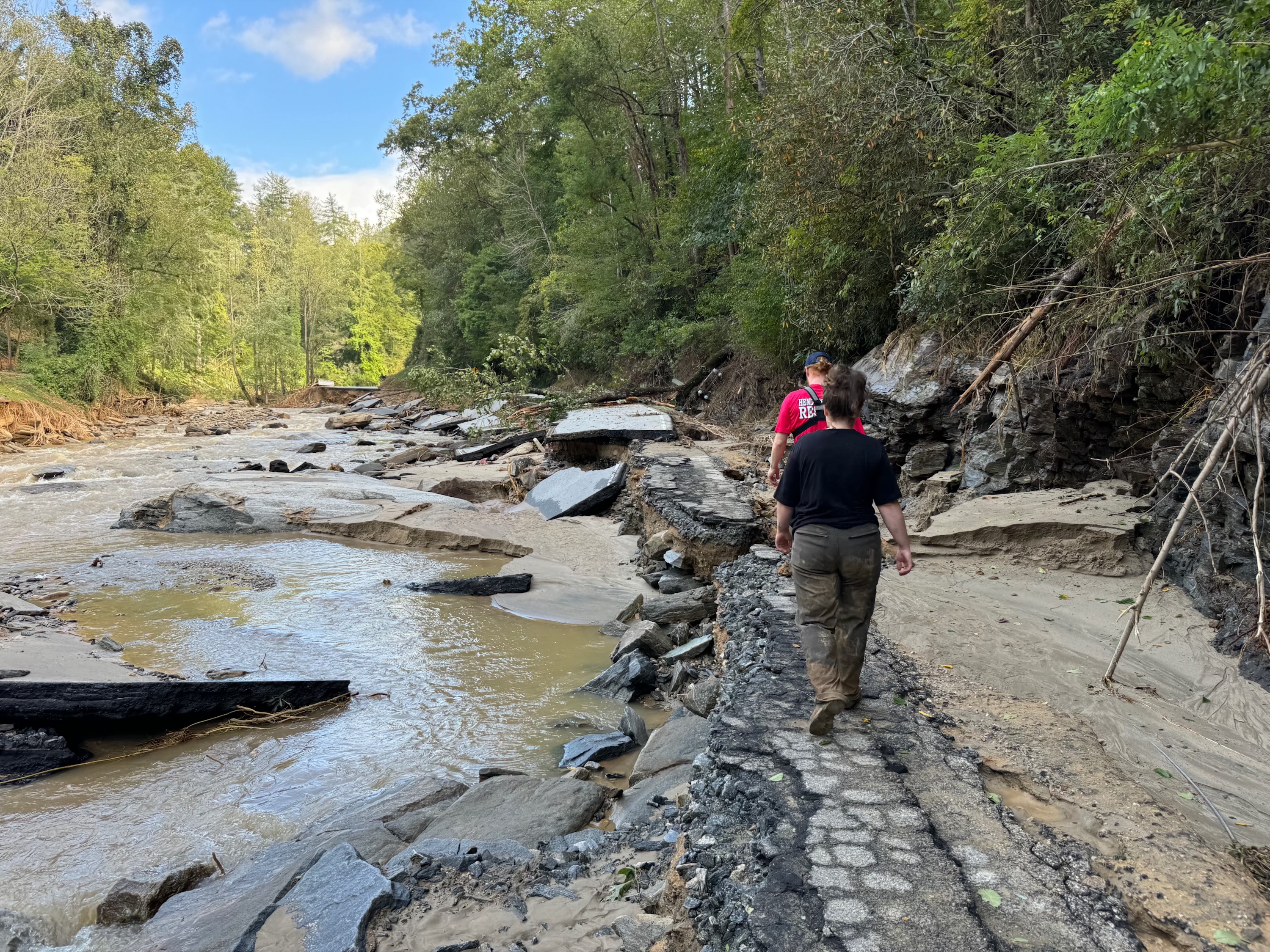 People walk alongside a washed out road