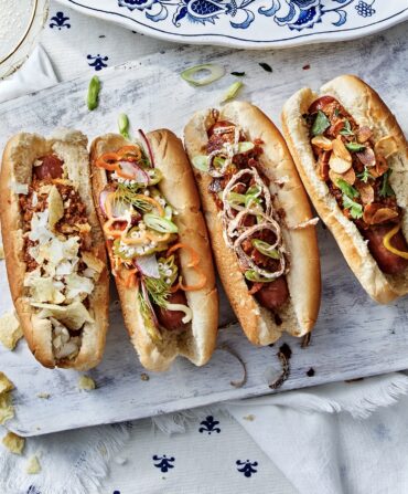 Two plates, one with hot dogs and one with oysters.