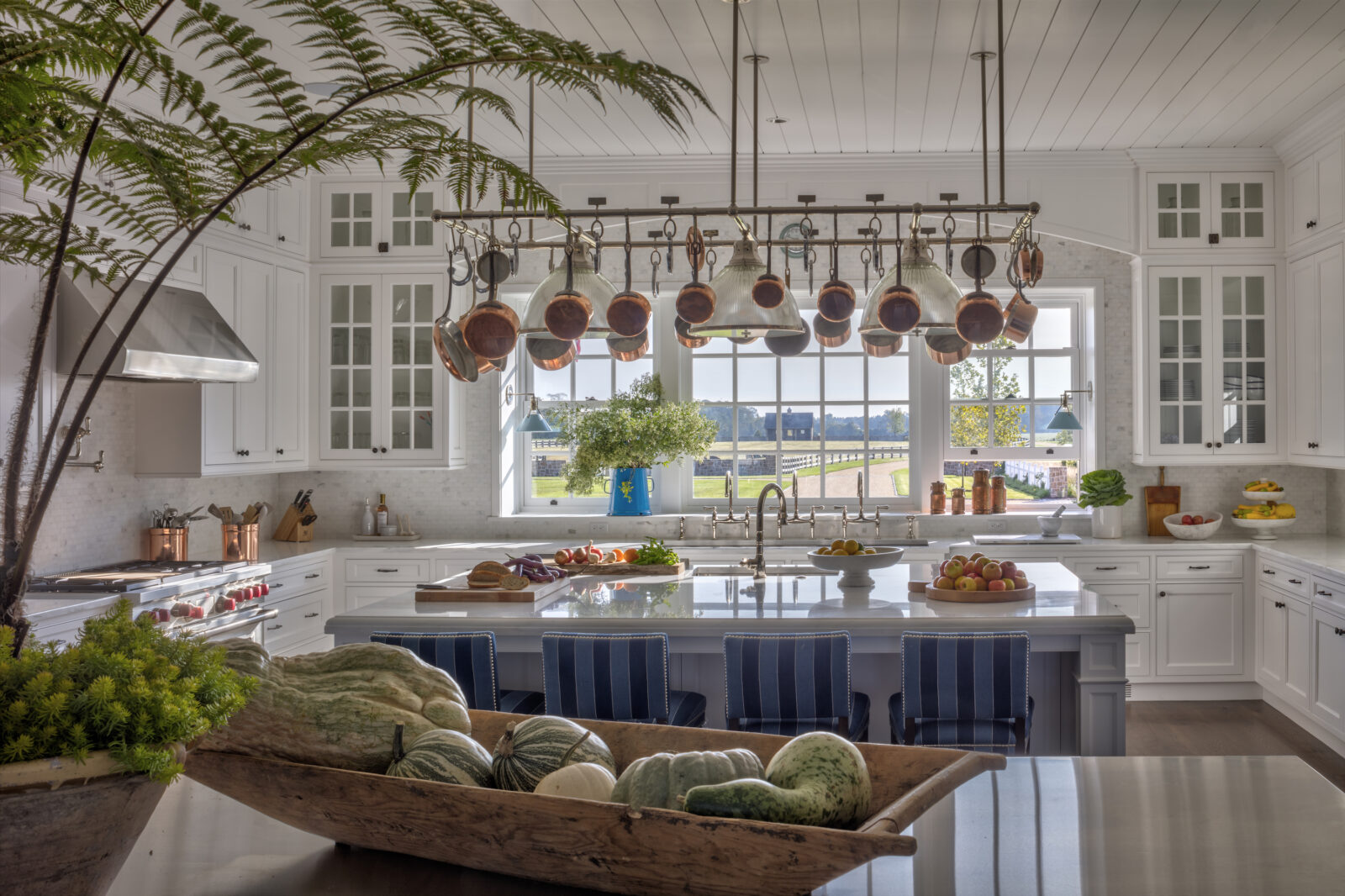 A kitchen with white marble tops and dark blue island cabinets.