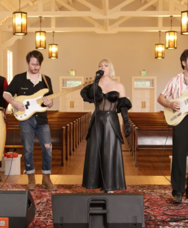 A band stands on a stage in a chapel