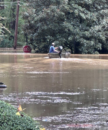 A person in a boat in a flooded neighborhood