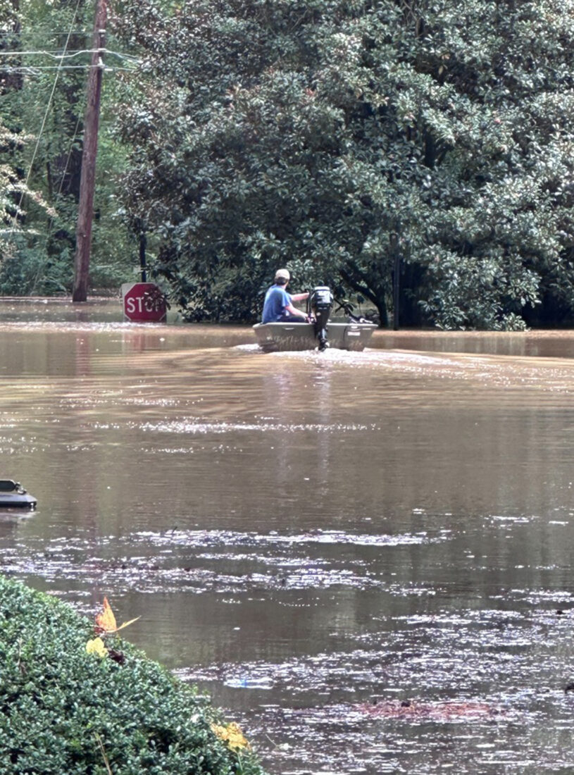 A person in a boat in a flooded neighborhood