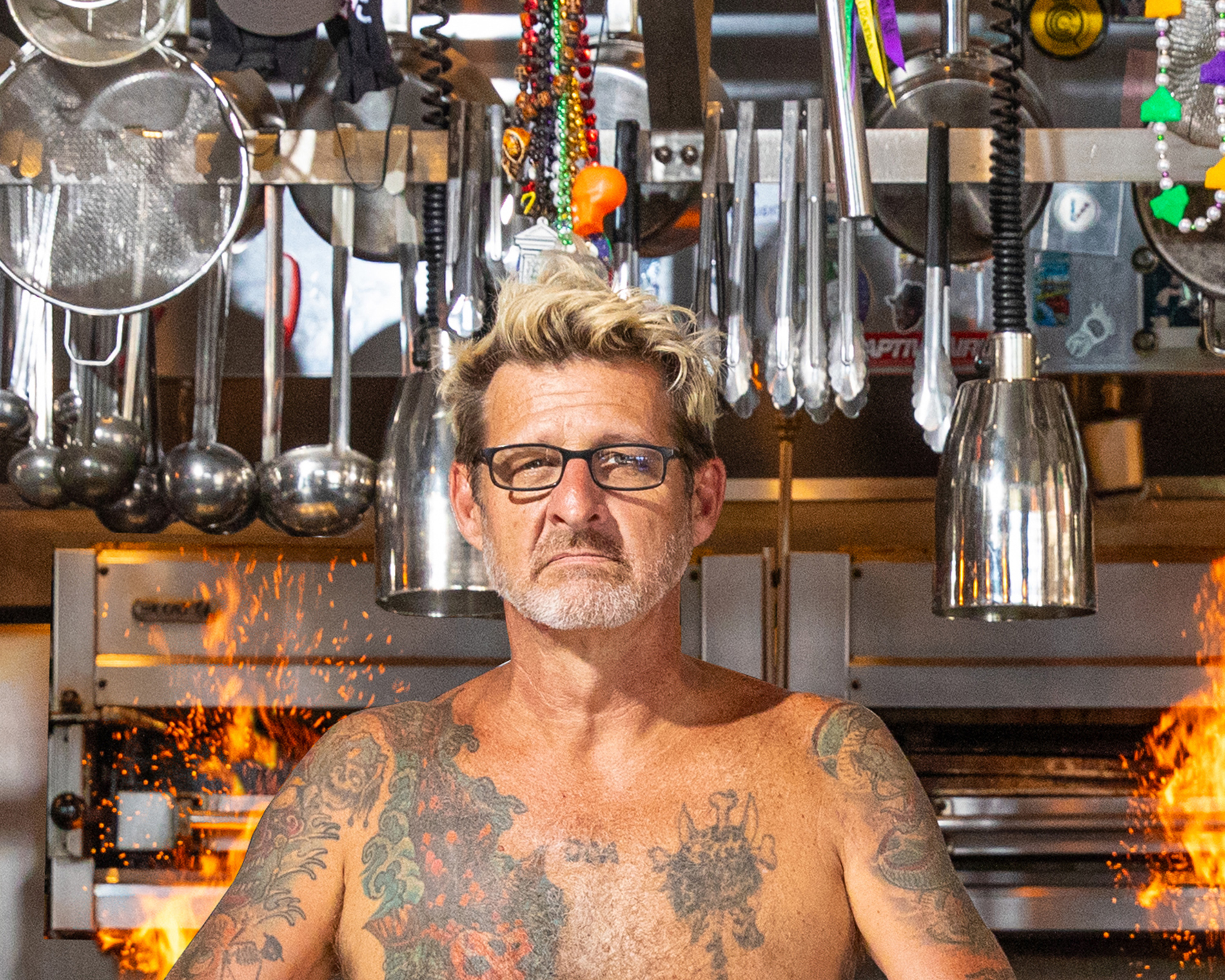 A man in front of cooking utensils and a grill