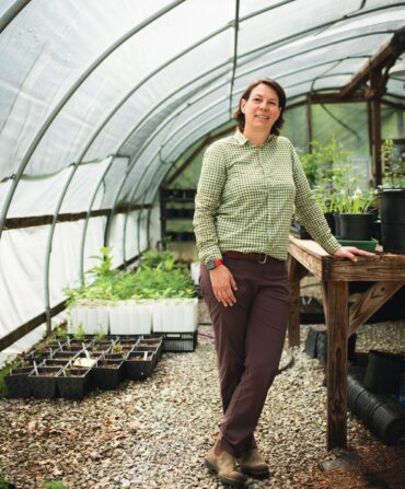 A woman stands in a greenhouse