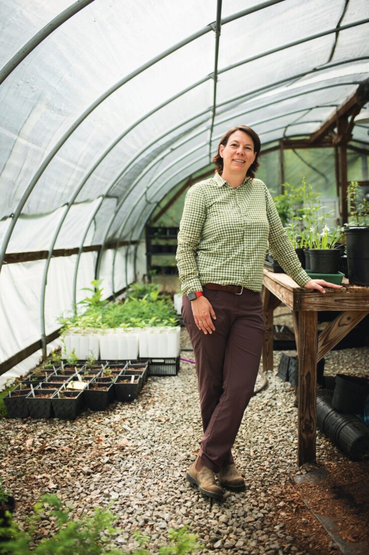 A woman stands in a greenhouse