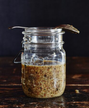 A mason jar halfway filled with Chunky Sweet Onion Jezebel Sauce.