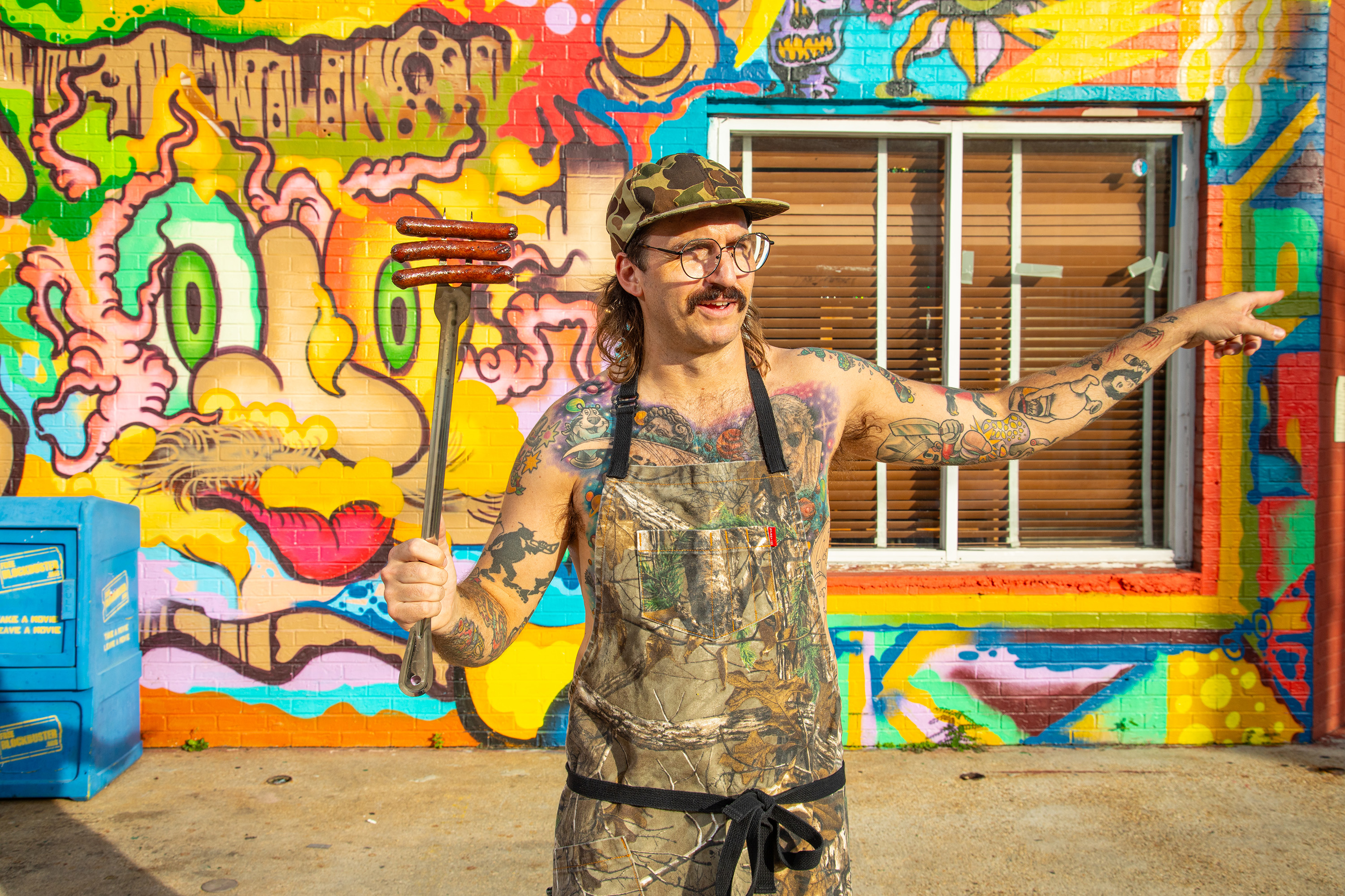 A man in overalls standing in front of a colorful wall