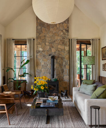 A living space with arched ceilings, a stone fireplace, and seating