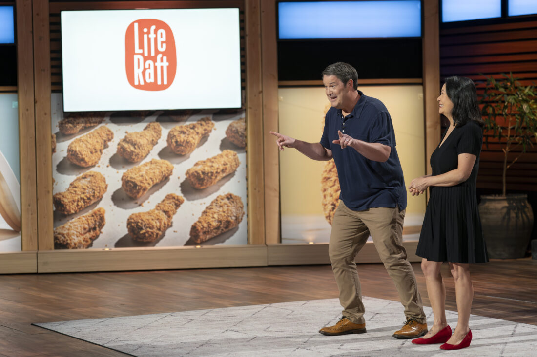 Two people stand on the stage of Shark Tank