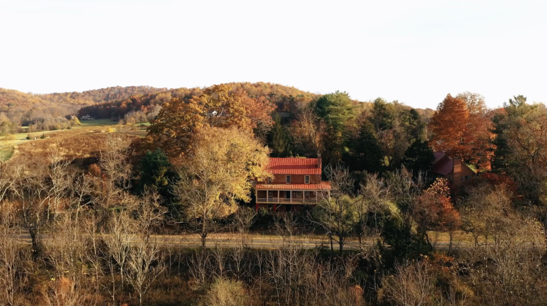 Fall trees around a red-roofed inn in a mountain landscape