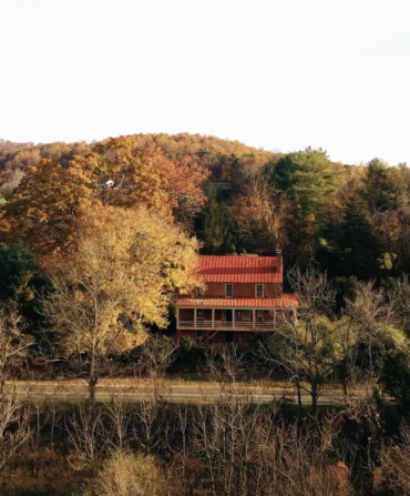 Fall trees around a red-roofed inn in a mountain landscape