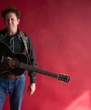 Folk Singer Abe Partridge poses with his guitar.