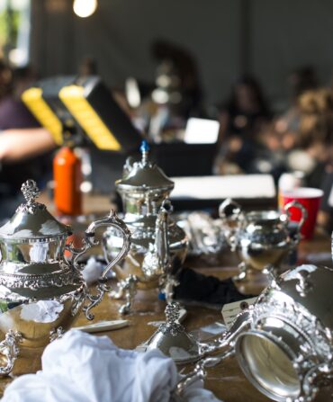 A spread of silver on a table with people cleaning it