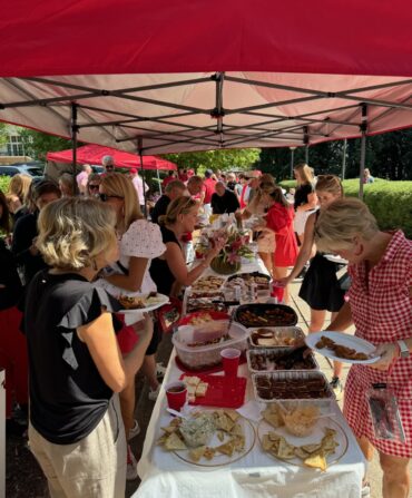 People gather around a tent with a spread of food