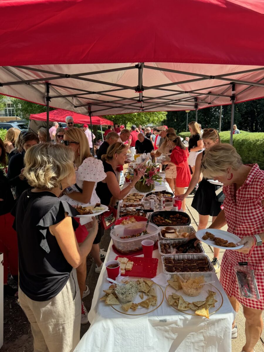 People gather around a tent with a spread of food