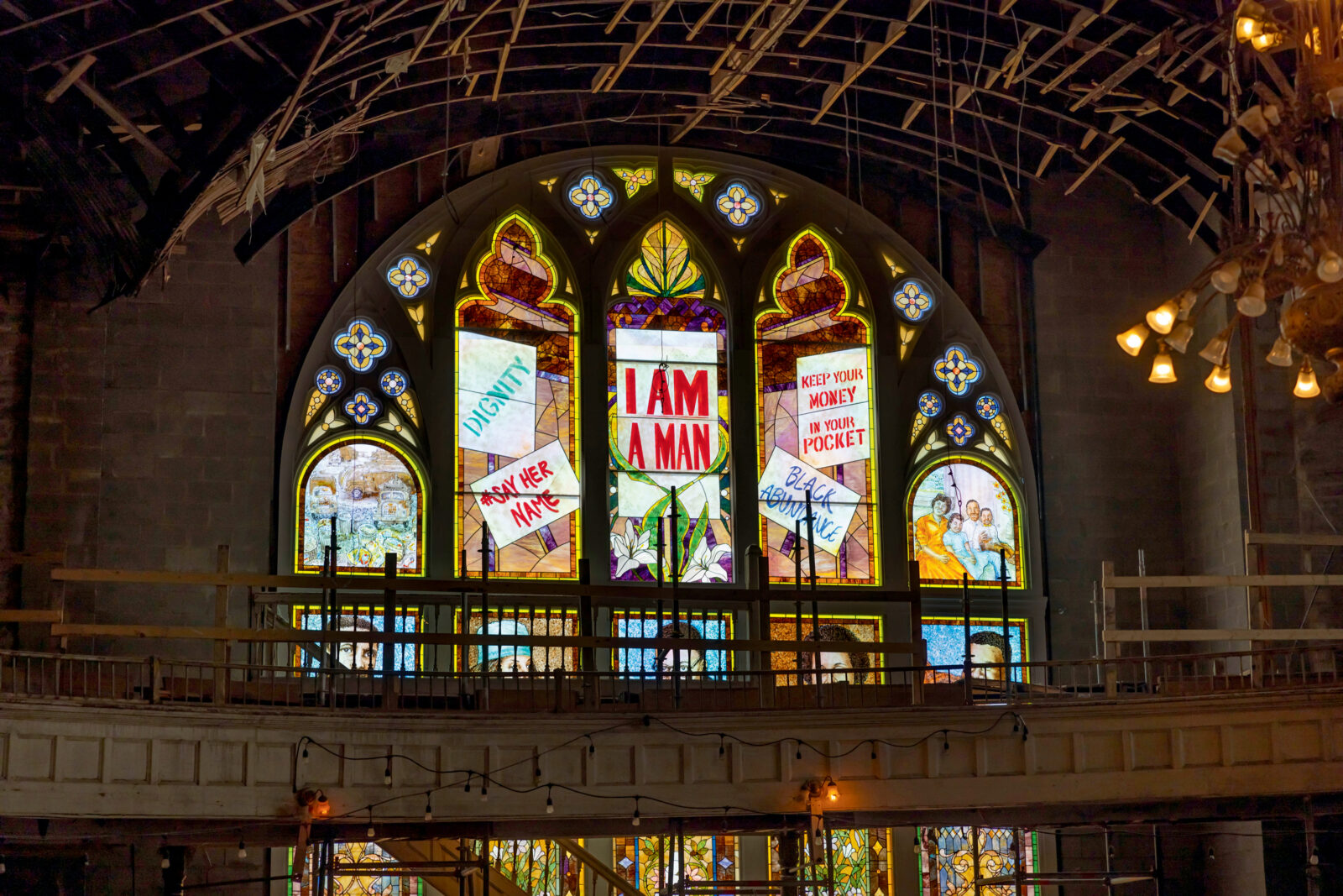 An arched stain glass window shows marching people