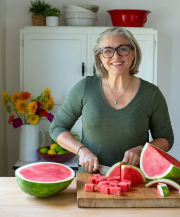 A picture of Virginia Willis cutting a watermelon.