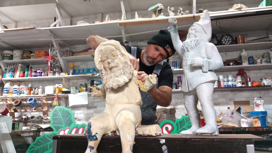 A man in a studio restores statues of gnomes