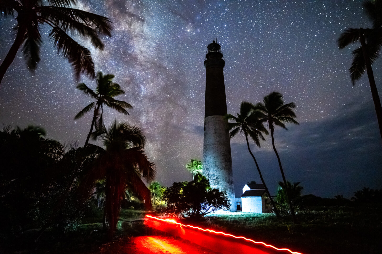 A starry night spreads out above a lighthouse