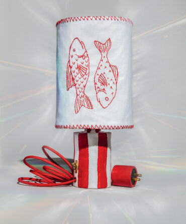 A red and white striped lamp with an embroidered fish shade