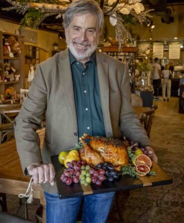 A man holds a board with a turkey on it