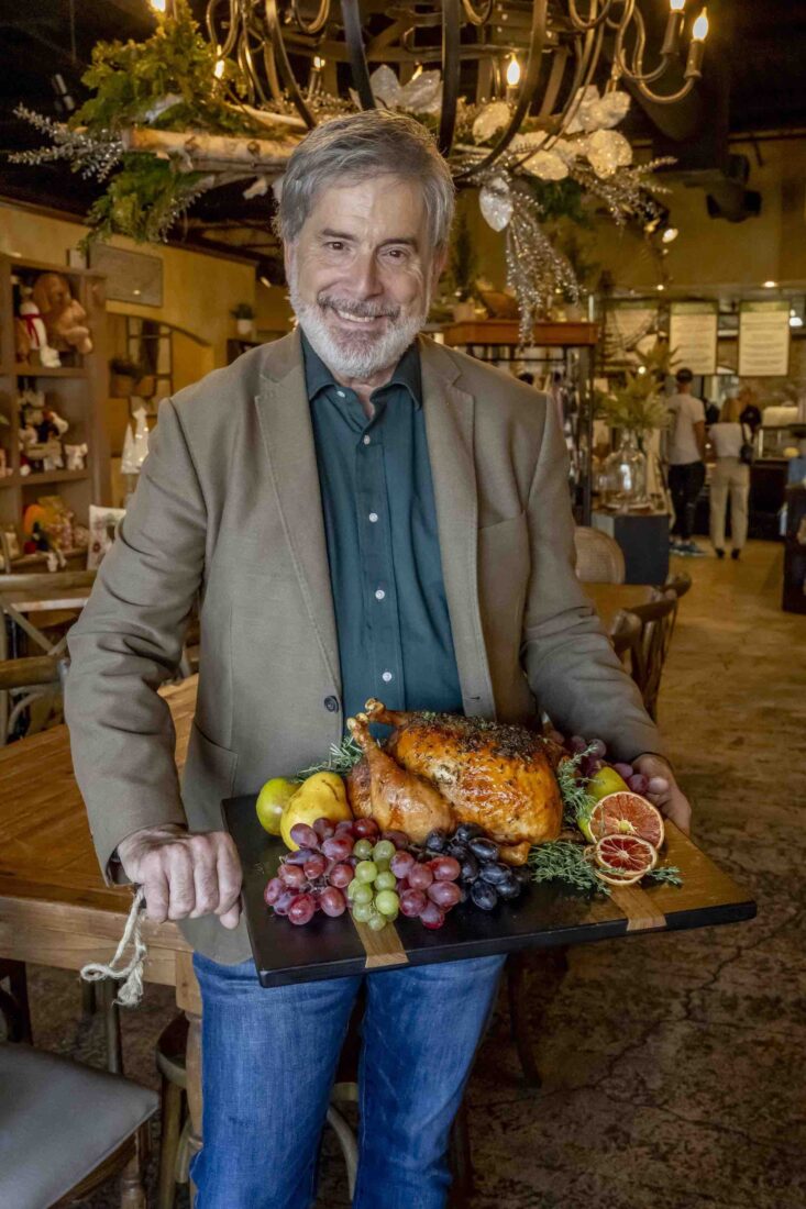 A man holds a board with a turkey on it