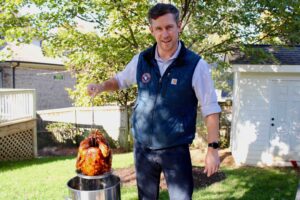 A man pulls a fried turkey out of a pot