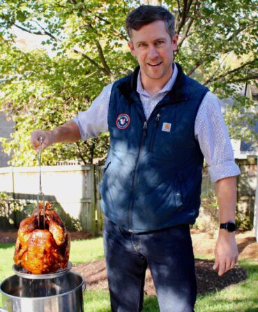 A man pulls a fried turkey out of a pot