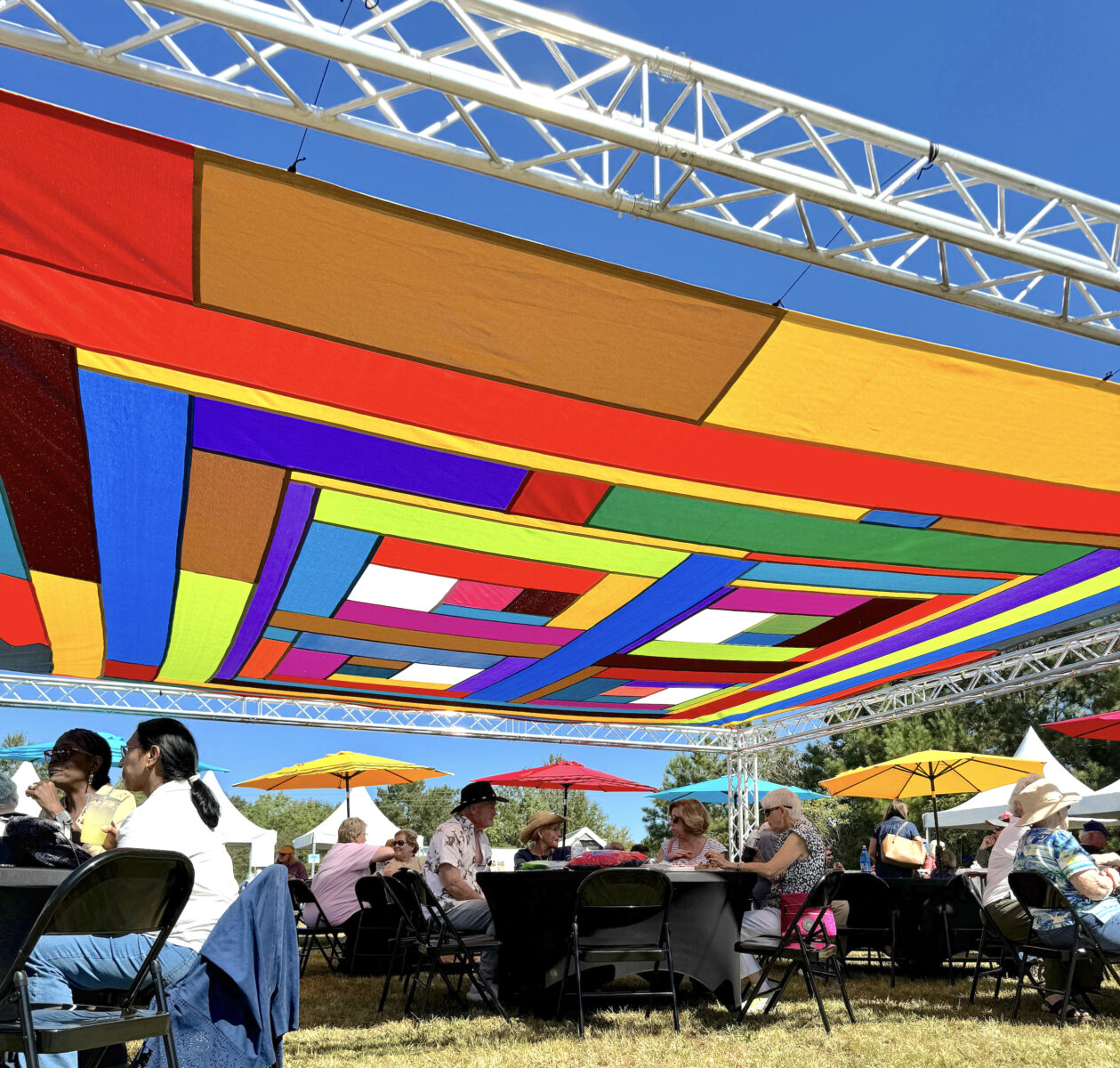 A quilted sunshade hangs above seated people