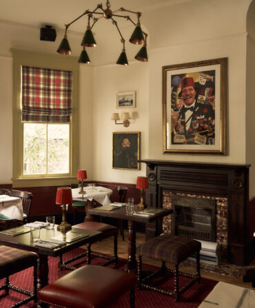 Inside a pub with red accents and portraits of men