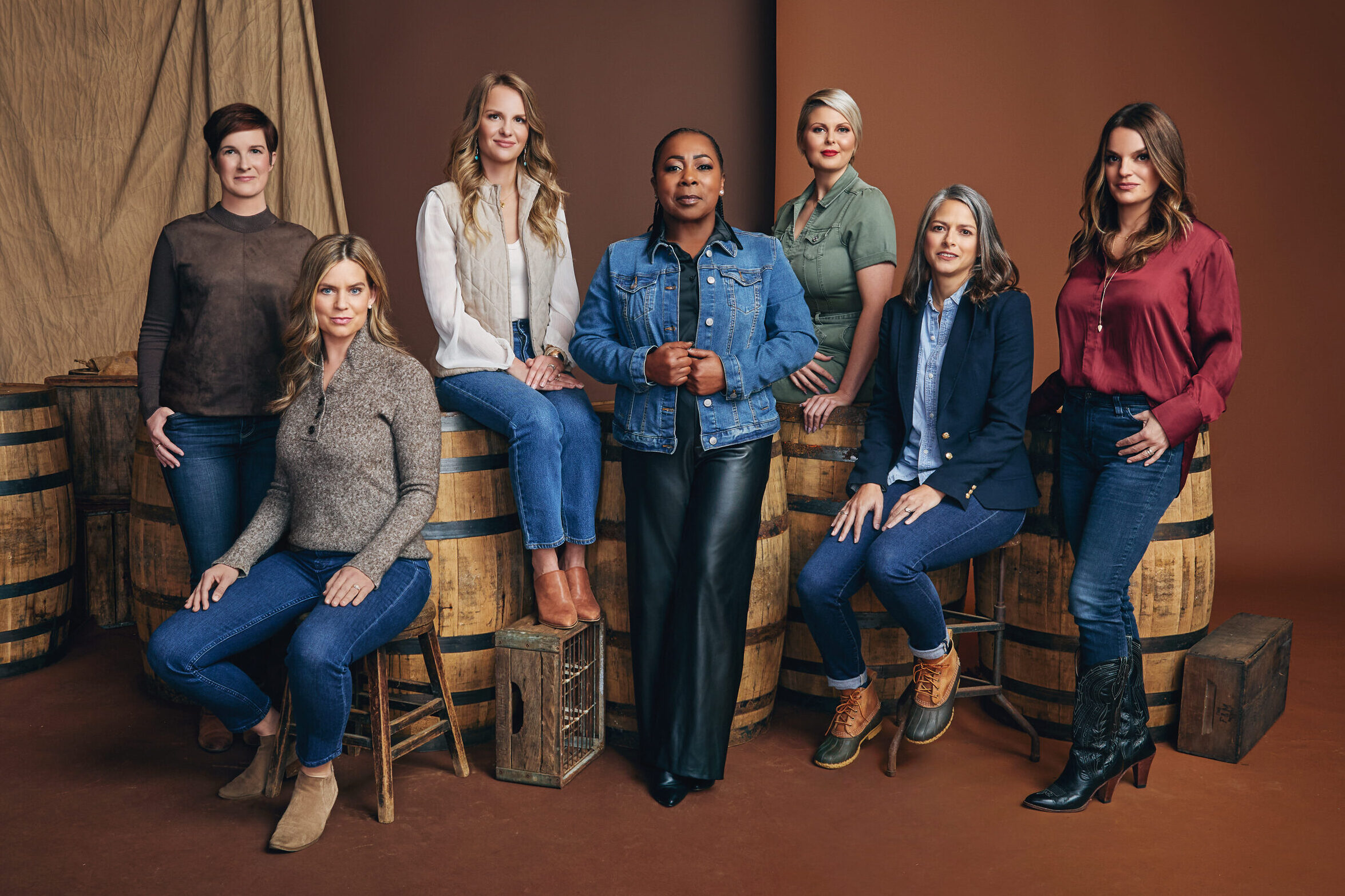 A group of women stand against a brown background