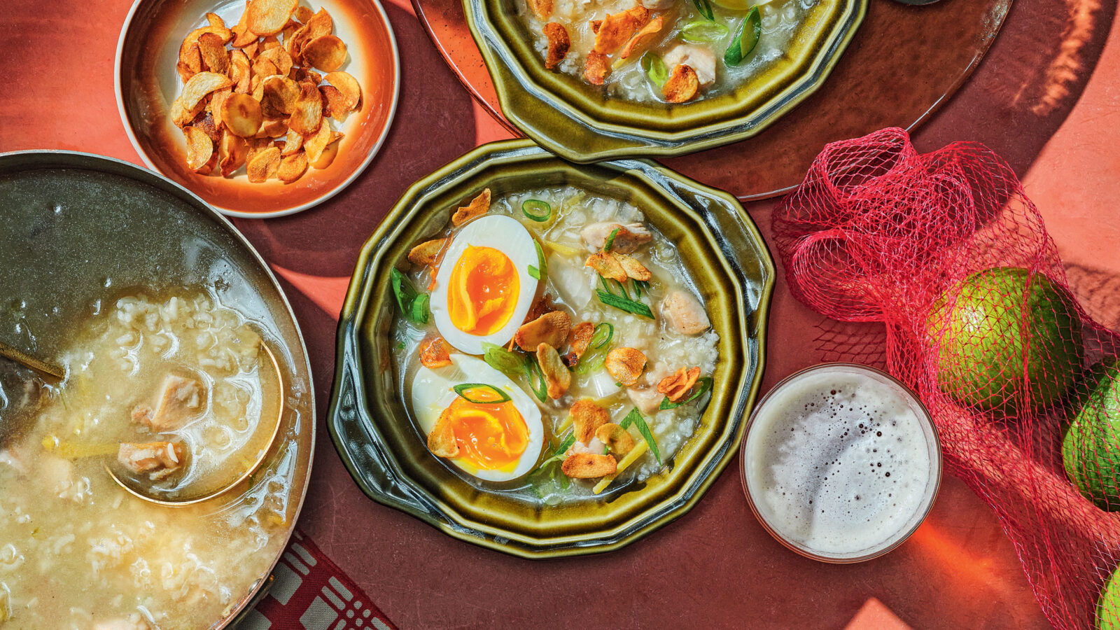 A spread of chicken porridge topped with eggs and bowls of garnishes