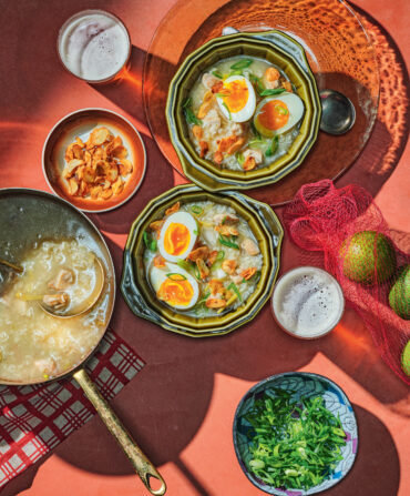 A spread of chicken porridge topped with eggs and bowls of garnishes