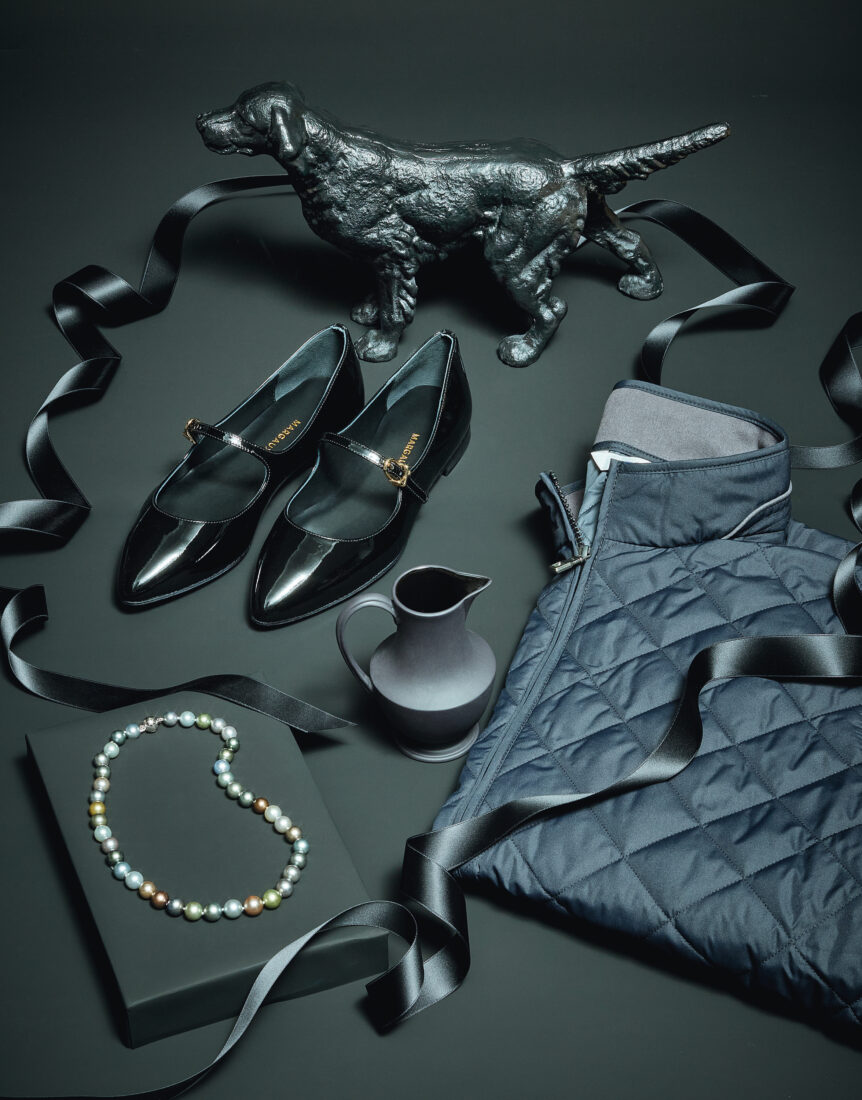 A black background with shoes, a necklace, a dog doorstop, and ribbon
