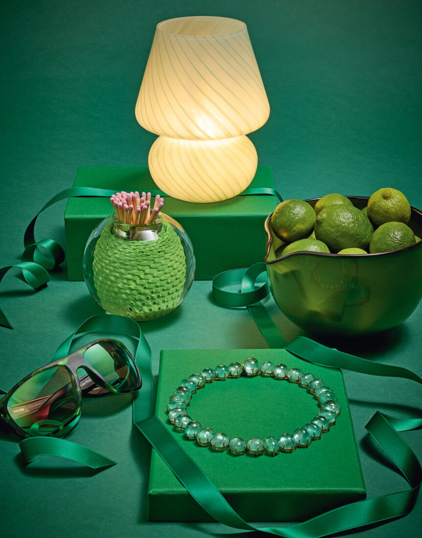 A green background with a lamp, matches, necklace, ribbon, sunglasses