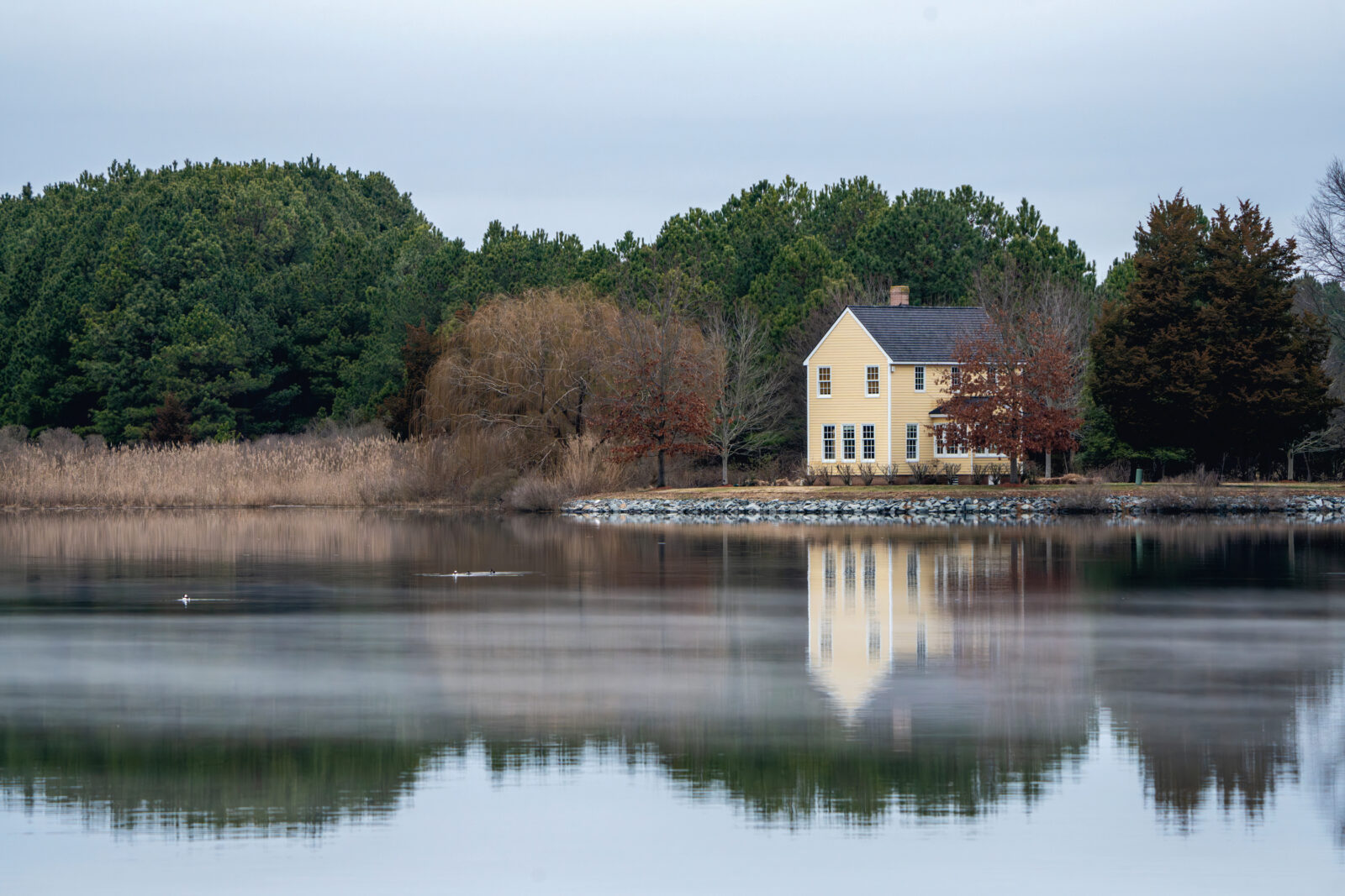 A tan house reflects into a river