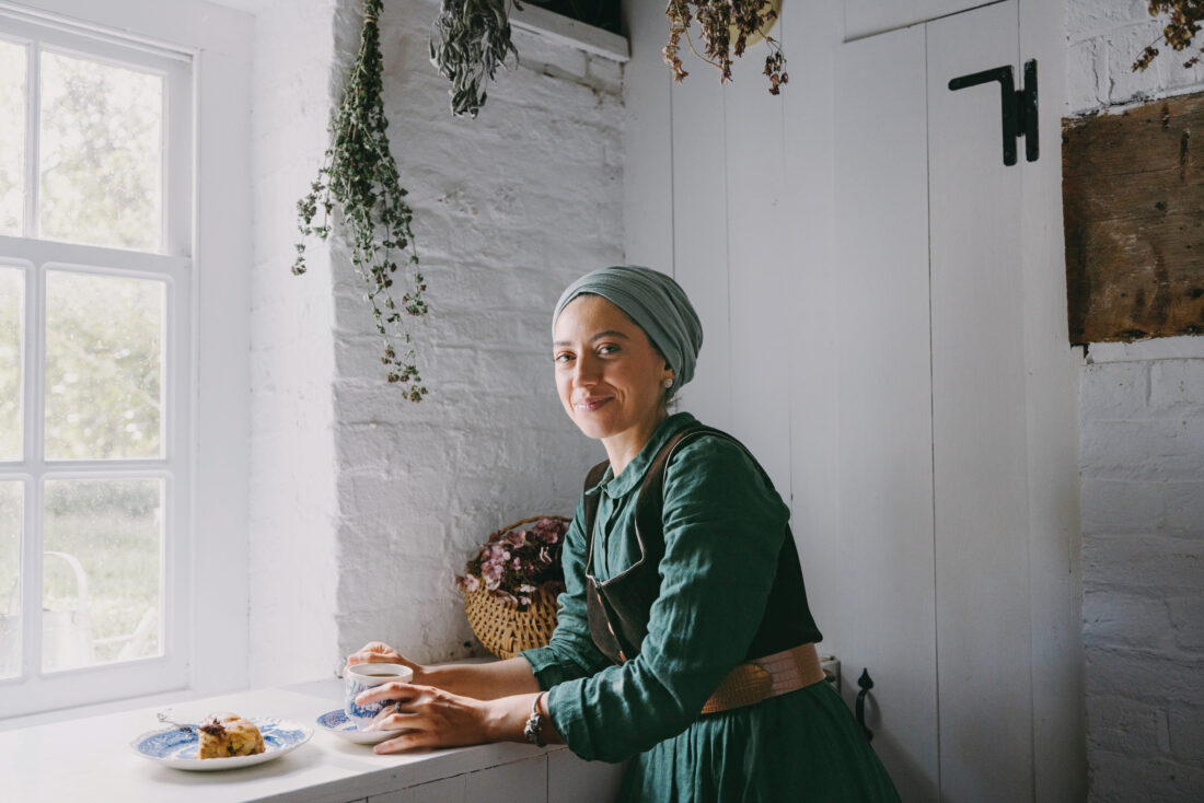 A woman holds a scone in a kitchen