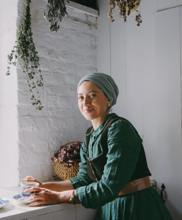 A woman holds a scone in a kitchen