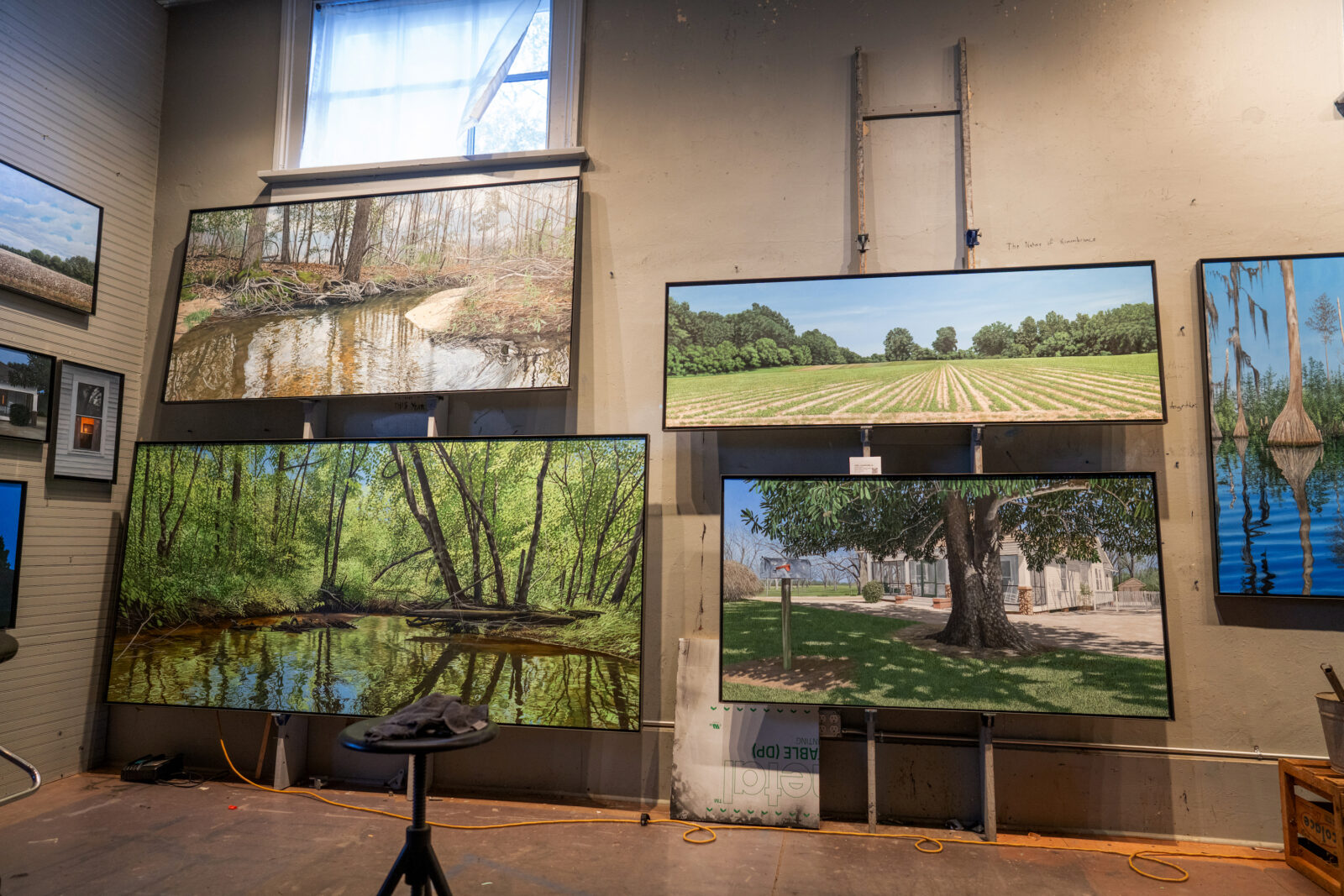 Landscape paintings hang in a studio