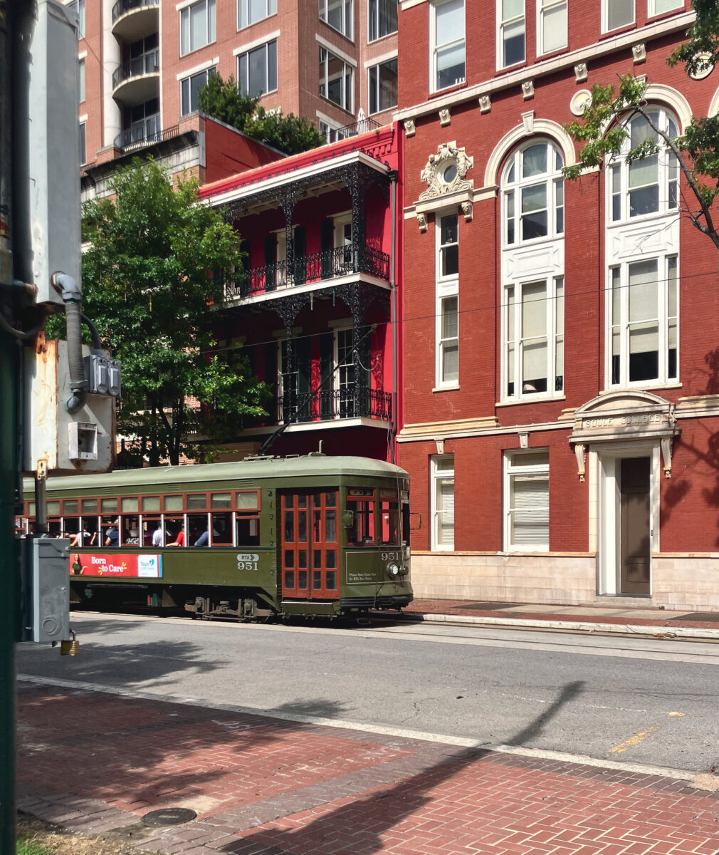 A green street car drives down a street